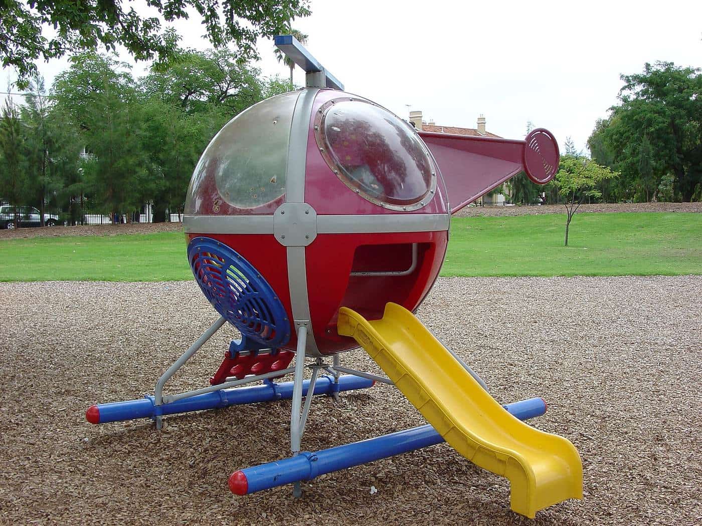 Children’s playground with a helicopter-shaped climbing frame and a yellow slide
